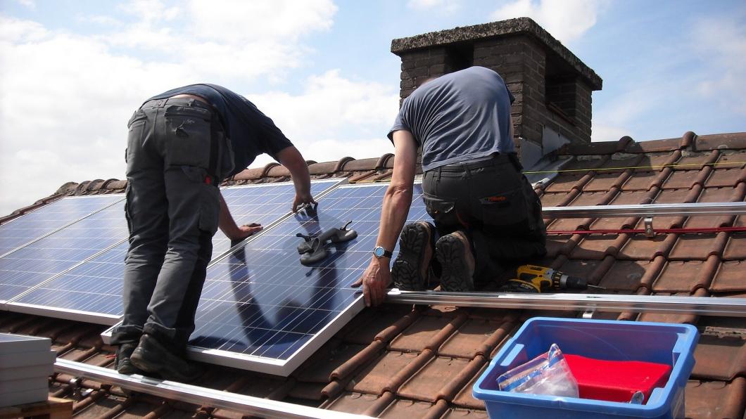 Twee mannen monteren zonnepanelen op een dak