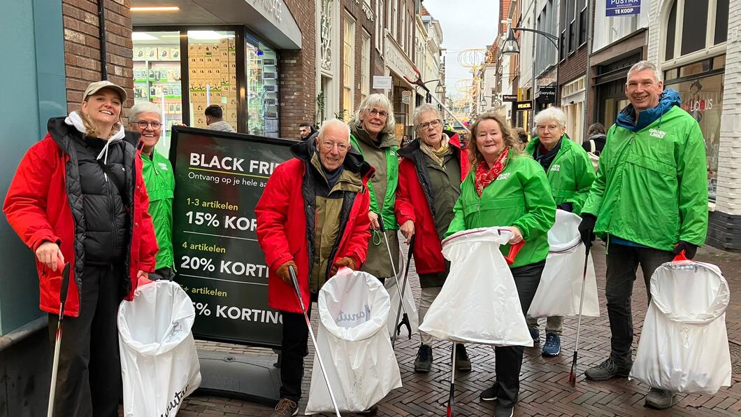 personen met vuilniszakken en rode en groene jassen
