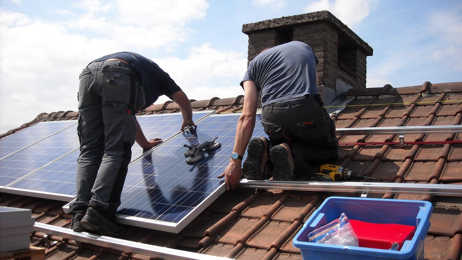 Twee mannen monteren zonnepanelen op een dak
