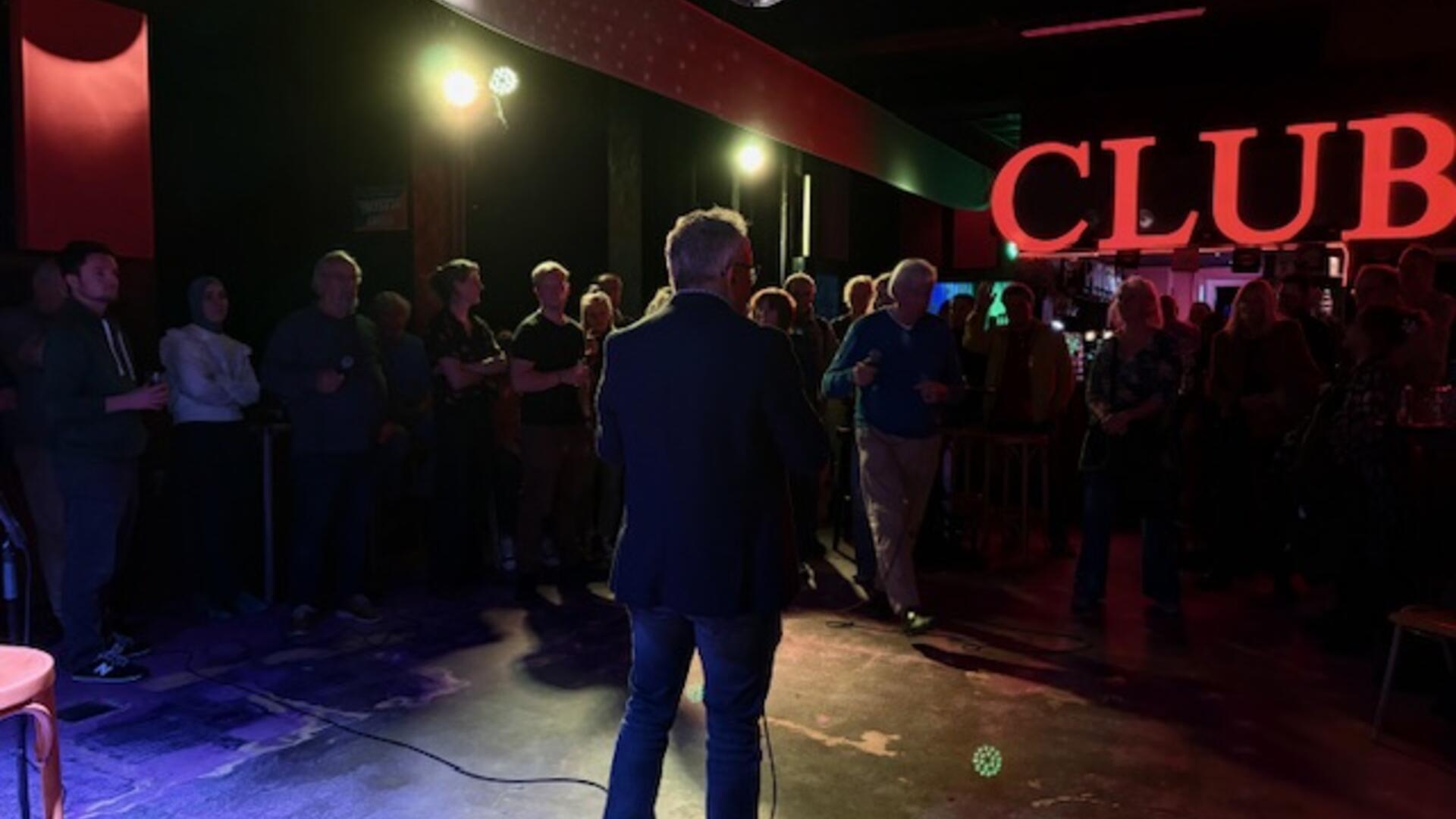 Donkere omgeving met omtrek van personen lichtgevende letters CLUB op de achtergrond
