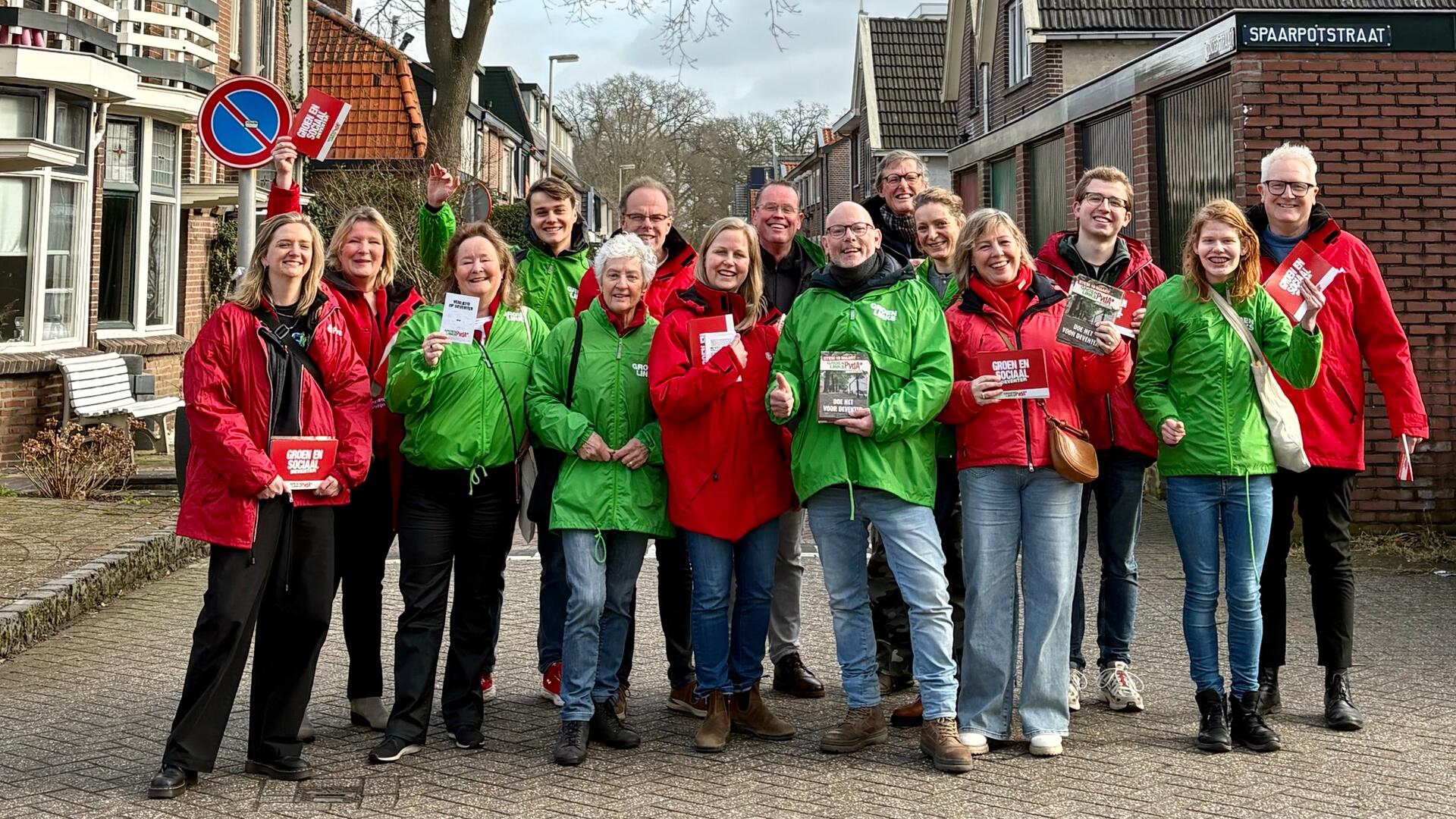 Personen met rode en groene jassen op straat op de Worp
